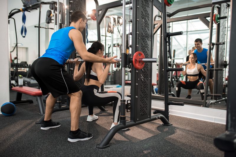 A gym instructor guiding a young woman through proper technique.