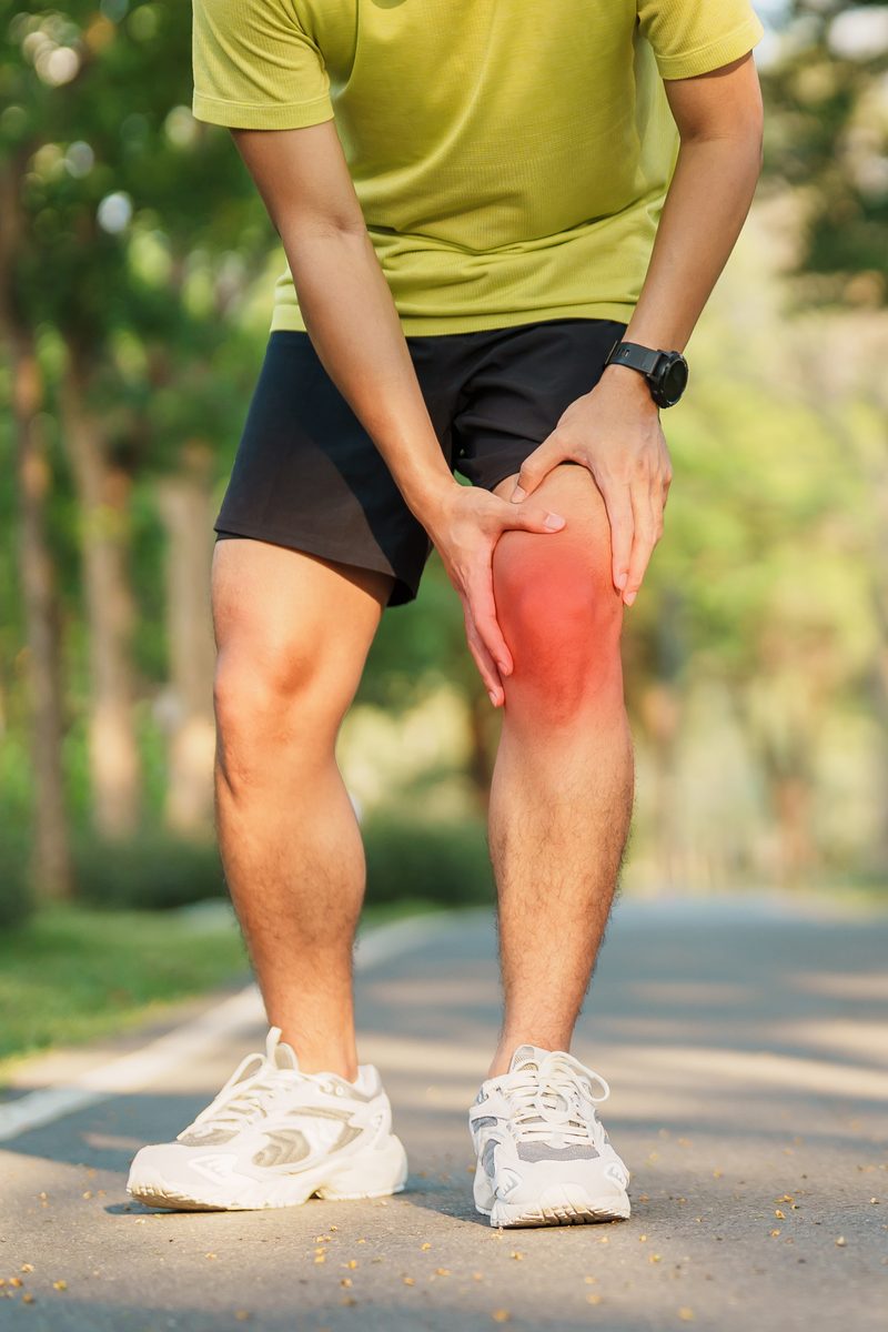 A man holding his knee after exercising outdoors.